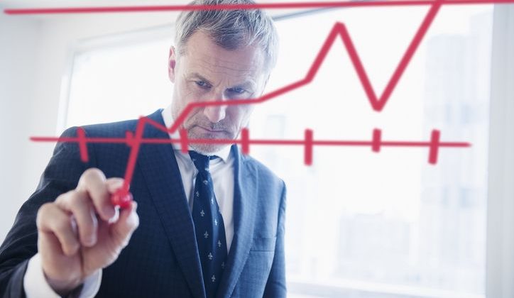 Businessman drawing regression chart on glass wall
