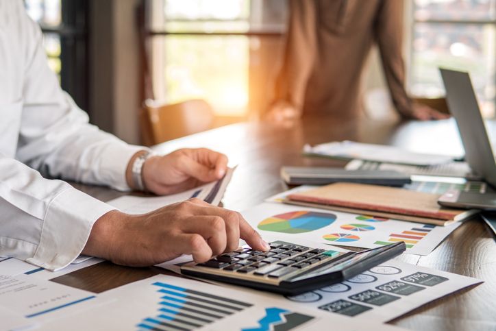 Professional working on financial report and colorful pie graph for investment risk analysis on office desk table