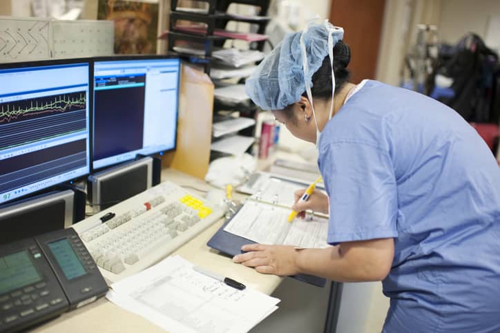 Hospital nurse prepares paperwork with statistical graphs on a computer