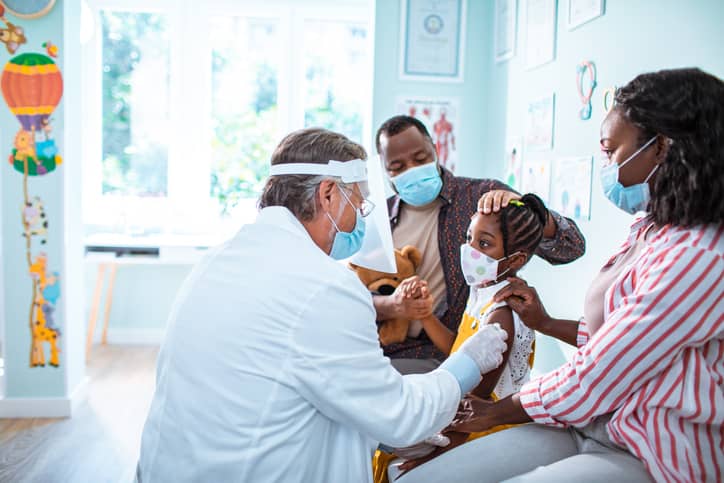 Closeup of a little girl being given a shot by her doctor.