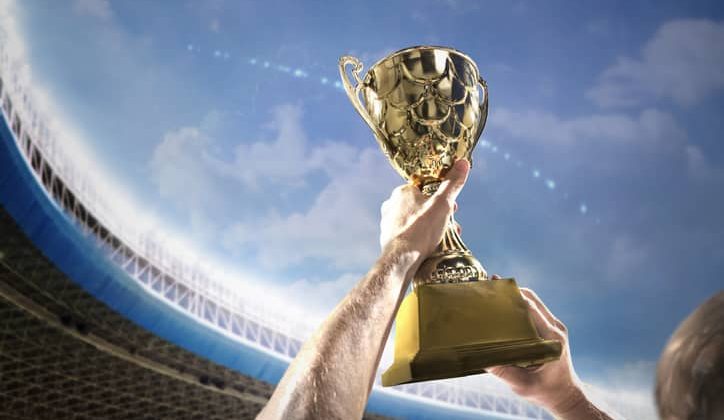 An athlete holds up a trophy in the air.