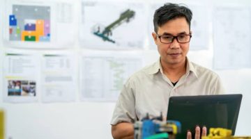 Asian engineer checking a computer on the manufacturing production floor